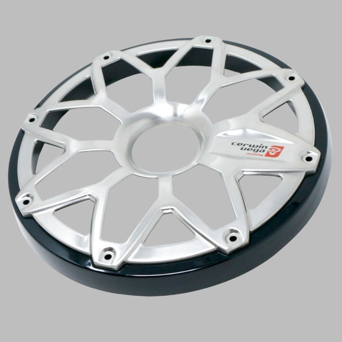 The RPM Stroker 6.5” Flush Mount Speaker Grill has a silver cover with an interlocking diamond pattern, bolt holes around the edge, and a small red logo with text on one segment against a plain gray background.