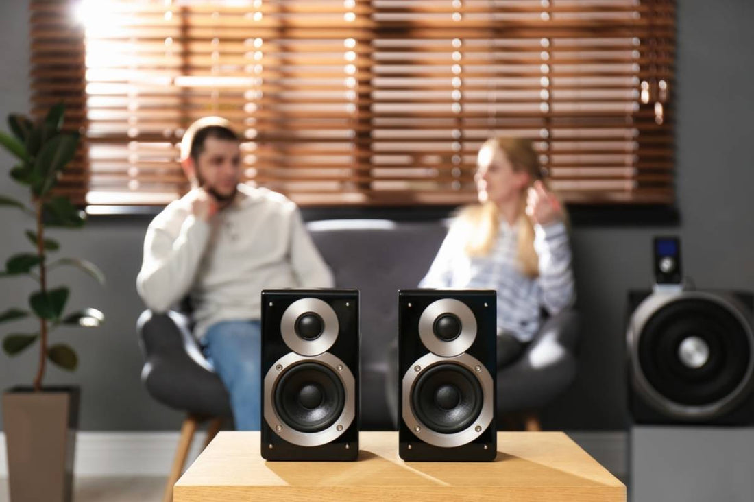 A man and woman listening to music behind a speaker system.