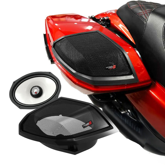 Close-up of a red Harley Davidson motorcycle with an integrated speaker system in the rear compartment. The 2024+ Harley Davidson® Cut-In Lid Kit with SM69F4 (4Ω) speakers has a black mesh cover and logo, showcasing its modern design. Below, the uncovered speaker reveals a white cone in a sleek black frame.