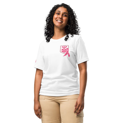 A smiling person with long curly hair is wearing a Cerwin-Vega Breast Cancer Awareness T-Shirt featuring a pink design of a hugging book and ribbon. They're paired with beige pants against a plain white background.