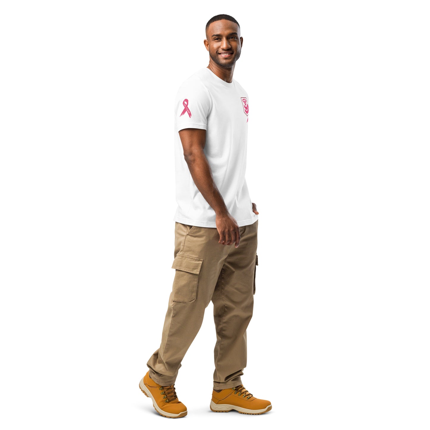 A man smiles against a white background, wearing a Cerwin-Vega Breast Cancer Awareness T-shirt with a pink ribbon on the sleeve. His tan cargo pants and boots complement the tucked-in shirt as he tilts his head slightly, looking directly at the camera.